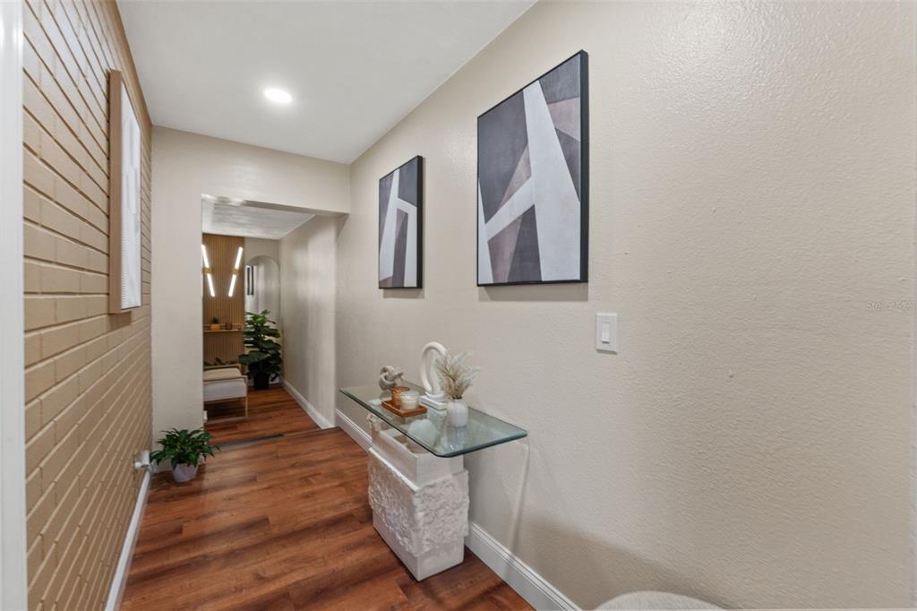 A hallway features wood-look flooring, a glass console table, and two framed abstract art pieces — 1721 S JEFFERSON AVENUE, CLEARWATER, FL