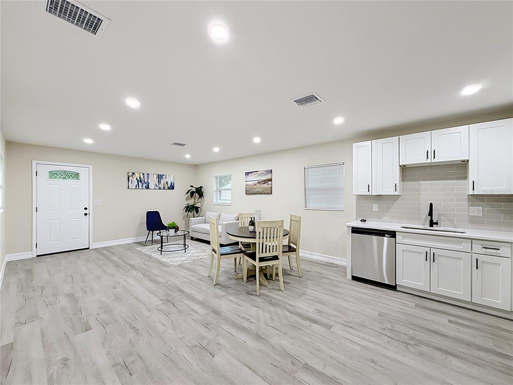 A kitchen and living area featuring white cabinets, stainless steel appliances, and light wood flooring — 38910 MERRELL AVENUE, UMATILLA, FL