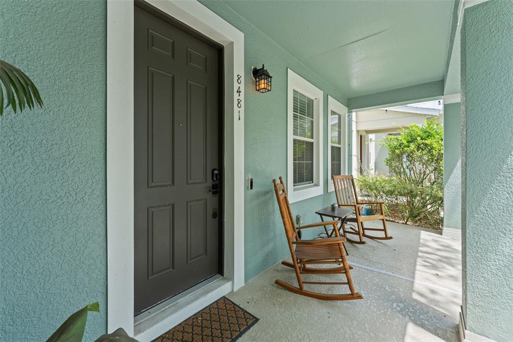 A front porch features a dark door, two wooden rocking chairs, and light green walls — 8481 LEELAND ARCHER BOULEVARD, ORLANDO, FL