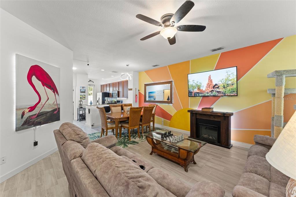 A living room features a sunburst mural, a fireplace, a television, and a dining area — 8481 LEELAND ARCHER BOULEVARD, ORLANDO, FL