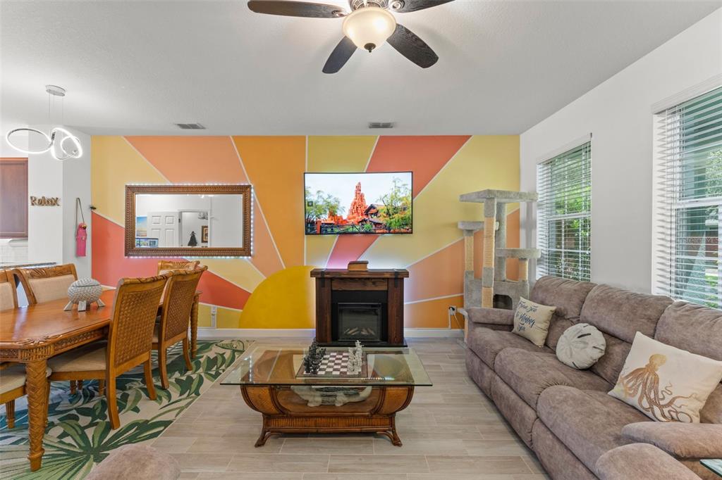 A living room features a sunburst mural, a wall-mounted television, a fireplace, and a sofa — 8481 LEELAND ARCHER BOULEVARD, ORLANDO, FL
