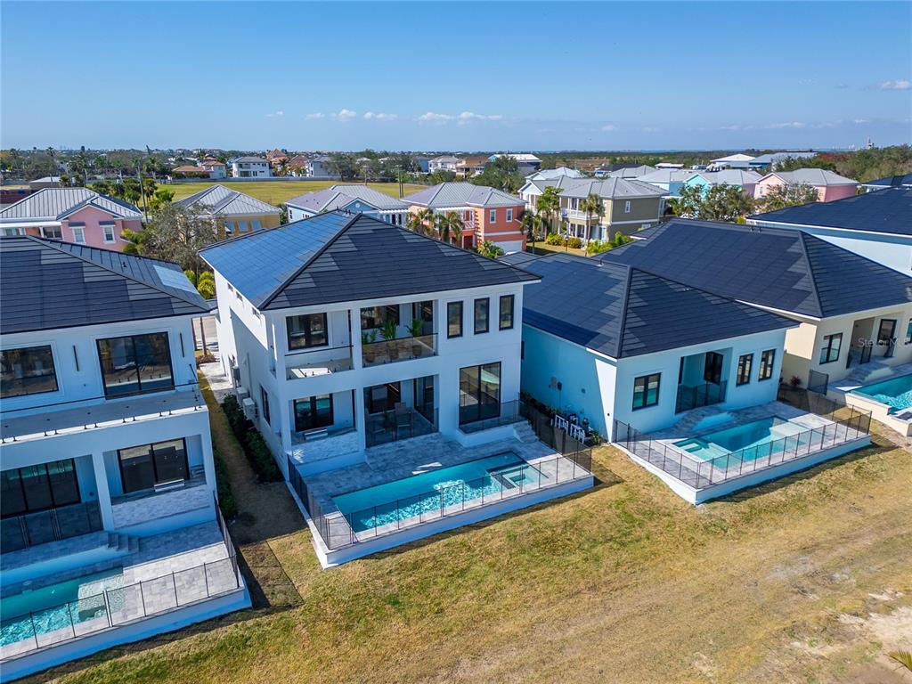 An aerial view of three modern houses with dark roofs, private pools, and fenced backyards — 6536 SIMONE SHORES CIRCLE, APOLLO BEACH, FL