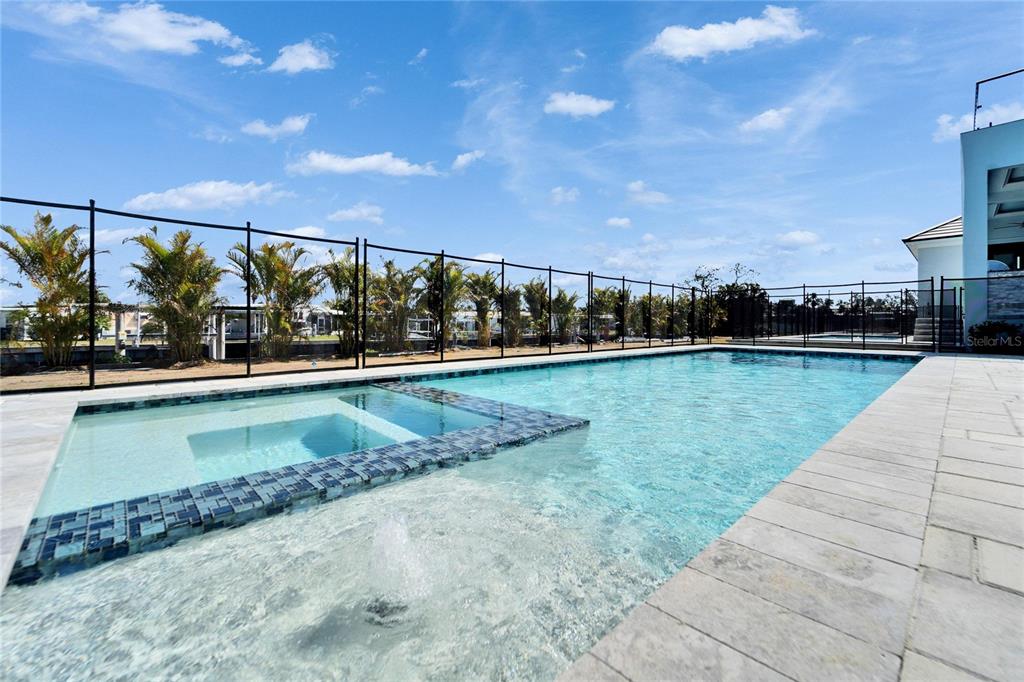 A swimming pool with an integrated spa and a fountain sits on a stone patio — 6536 SIMONE SHORES CIRCLE, APOLLO BEACH, FL