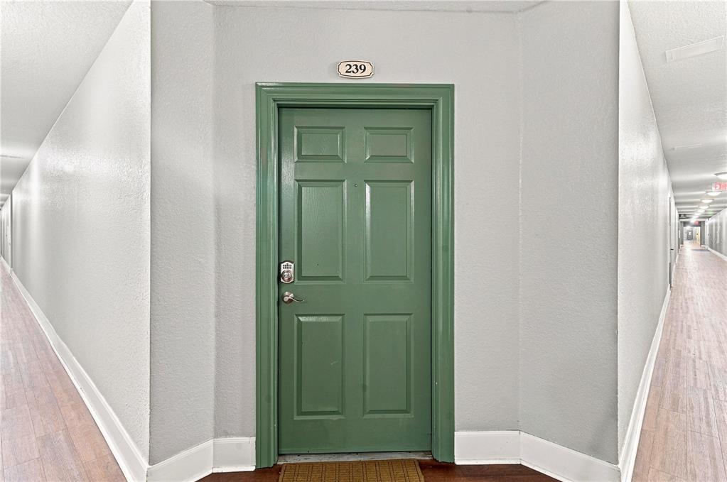 A green apartment door with the number 239 is centered in a long, brightly lit hallway — 860 N ORANGE AVENUE UNIT 239, ORLANDO, FL