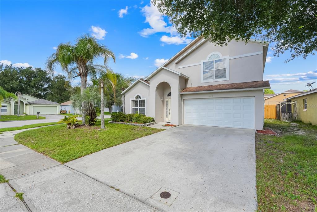 A two-story suburban house with a concrete driveway, a two-car garage, and palm trees — 1324 WHITEWOOD WAY WAY, CLERMONT, FL