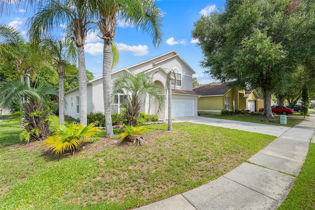 A beige two-story house with a white garage and palm trees in the front yard — 1324 WHITEWOOD WAY WAY, CLERMONT, FL