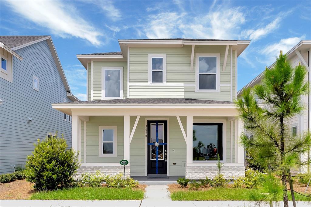 A two-story house with light green siding, a front porch, and a dark front door — 3050 VOYAGER AVENUE, ST CLOUD, FL