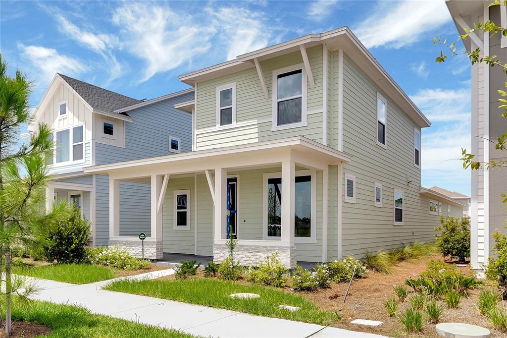 A light green two-story house with a front porch and white trim under a blue sky — 3050 VOYAGER AVENUE, ST CLOUD, FL
