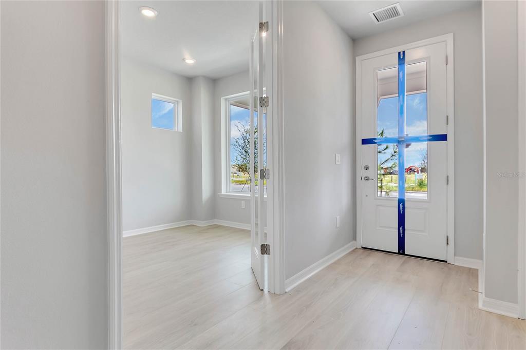 An entryway with light wood flooring leads to a room with French doors and windows — 3050 VOYAGER AVENUE, ST CLOUD, FL