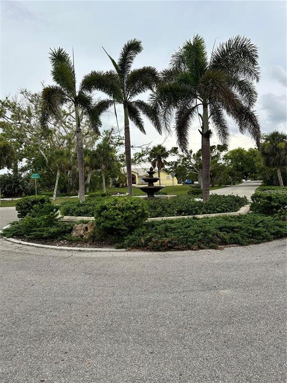 A circular driveway features a central garden island with a fountain and three palm trees — 120 SPANIARDS ROAD, PLACIDA, FL