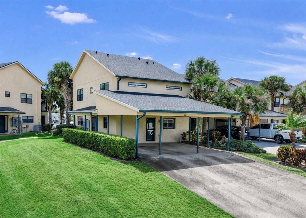 A two-story tan townhouse with a covered carport and a green lawn in front — 626 YARDARM DRIVE UNIT 13, APOLLO BEACH, FL