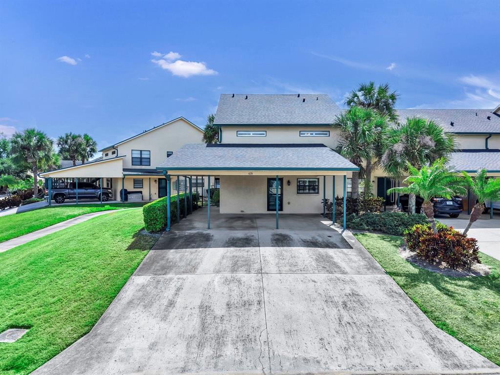 A two-story townhouse with a concrete driveway and a covered carport under a blue sky — 626 YARDARM DRIVE UNIT 13, APOLLO BEACH, FL