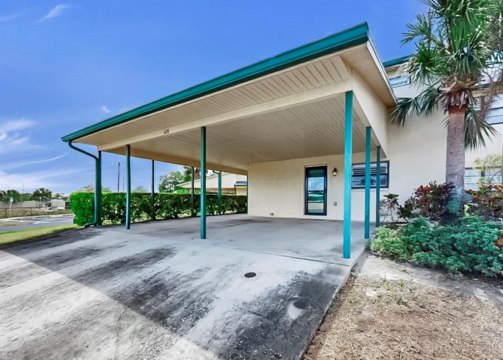 A concrete driveway leads to a covered carport attached to the side of a building — 626 YARDARM DRIVE UNIT 13, APOLLO BEACH, FL