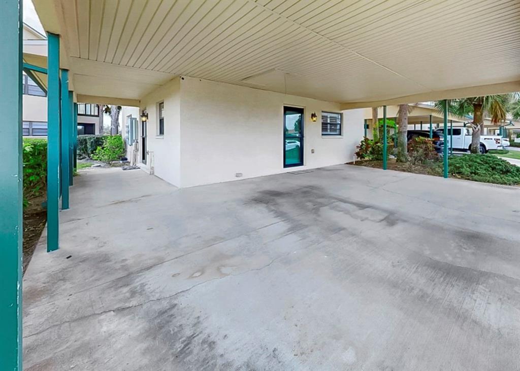 A concrete carport with teal support posts leads to a building entrance with a door — 626 YARDARM DRIVE UNIT 13, APOLLO BEACH, FL