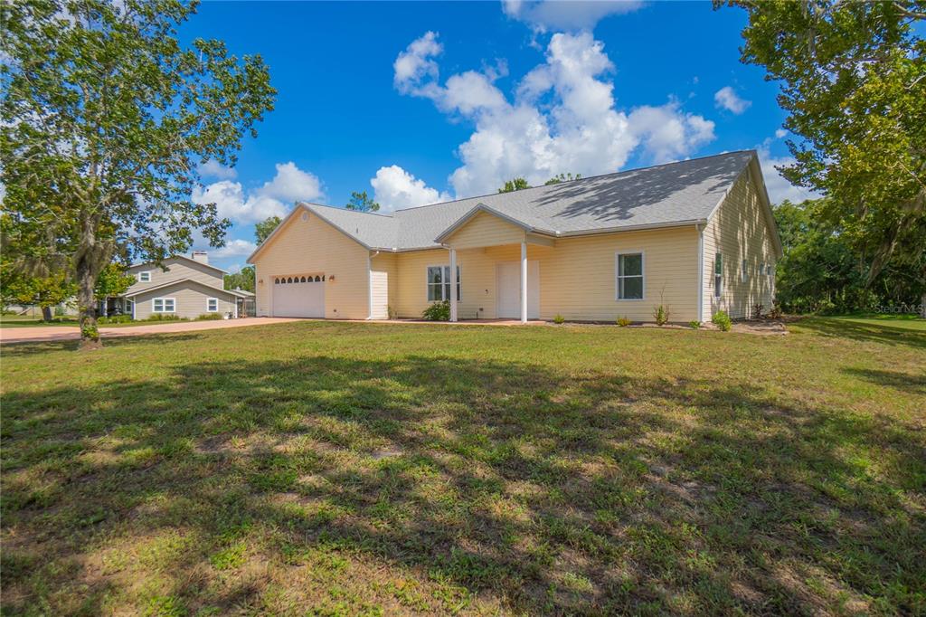 A light yellow, single-story house with a white garage and a covered front entryway — 12718 SUGAR CREEK BOULEVARD, HUDSON, FL