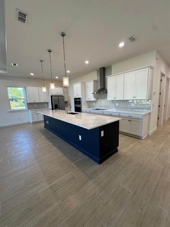 A kitchen features a dark blue island, white cabinetry, stainless steel appliances, and wood-look tile — 1138 CLIFFHAVEN COURT, ORMOND BEACH, FL