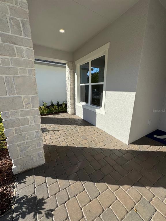 A covered entryway features stone-clad columns and a paved patio floor — 1138 CLIFFHAVEN COURT, ORMOND BEACH, FL