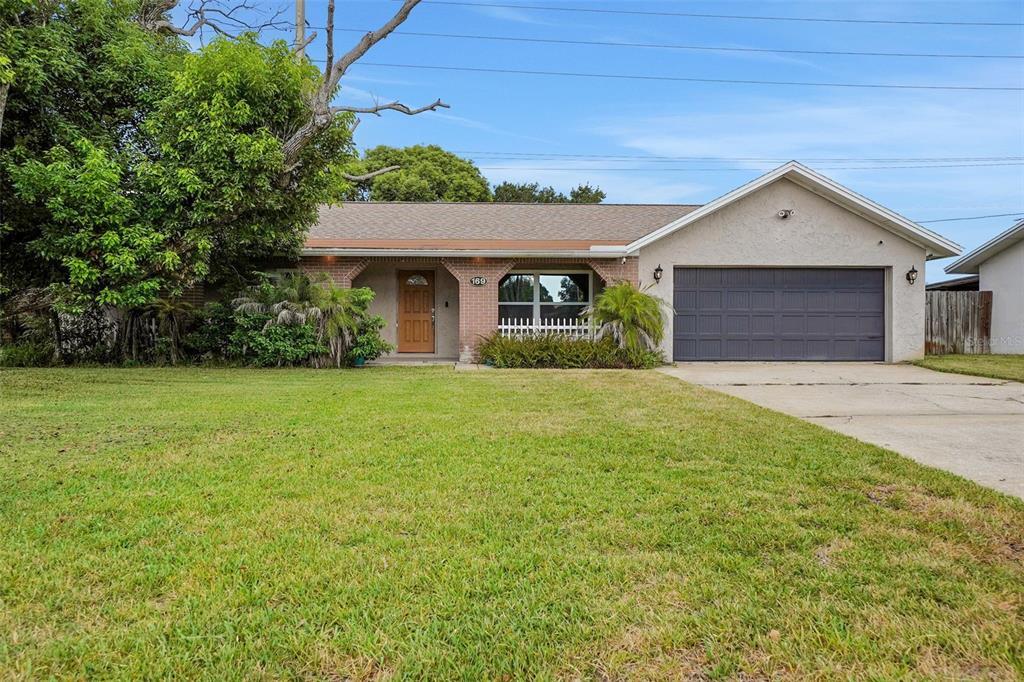 A single-story house with a brown front door, a two-car garage, and a large lawn — 169 LEISURE CIRCLE, PORT ORANGE, FL
