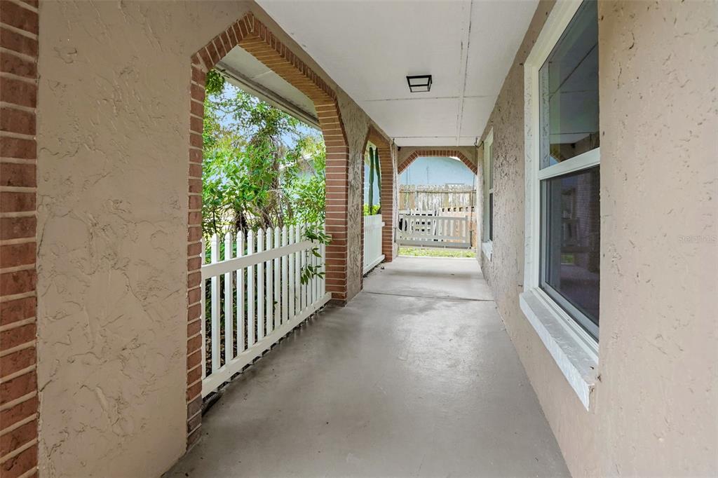 A covered porch features a white picket fence, brick-trimmed arches, and a concrete floor — 169 LEISURE CIRCLE, PORT ORANGE, FL