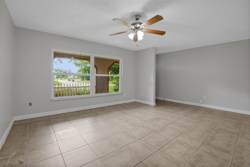 An empty room with light gray walls, large windows, and beige tile flooring — 169 LEISURE CIRCLE, PORT ORANGE, FL