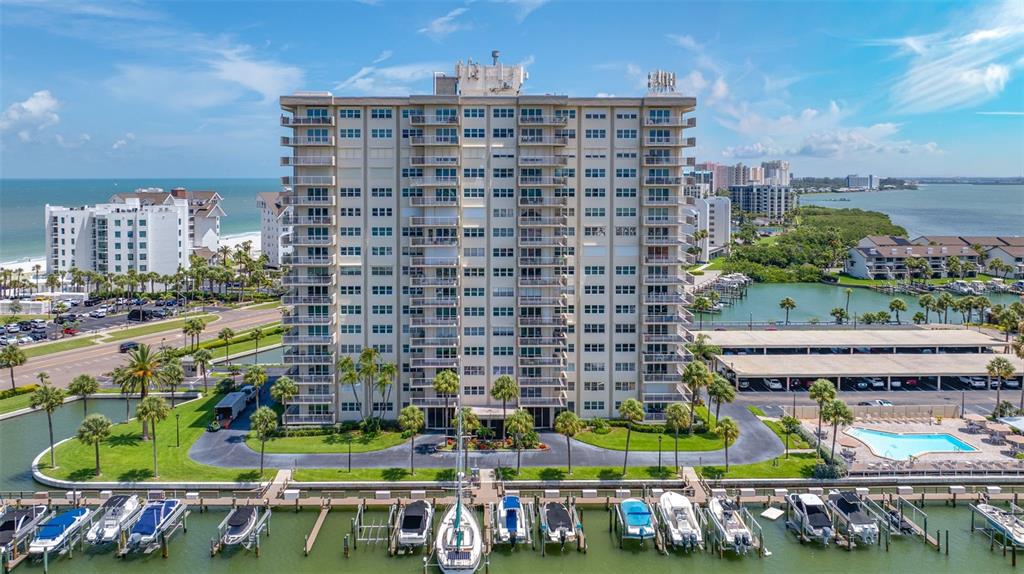 An aerial view of a tall residential building with a boat dock and swimming pool — 1621 GULF BOULEVARD UNIT 501, CLEARWATER BEACH, FL