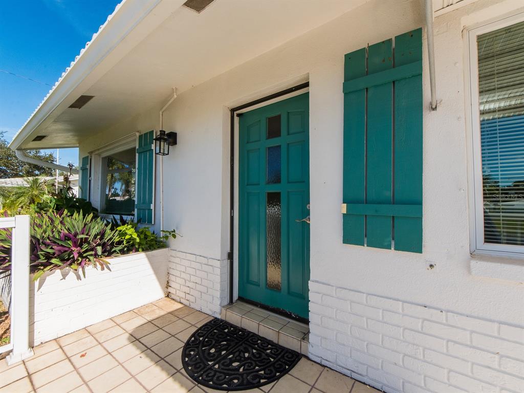 A teal front door with shutters and a tiled porch entrance to a white house — 9157 140TH WAY, SEMINOLE, FL