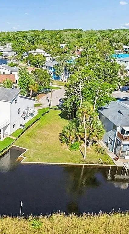 An aerial view shows a vacant waterfront lot situated between two houses — 5243 TROPICAL POINT, WEEKI WACHEE, FL