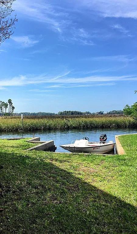 A small motorboat is docked in a canal next to a grassy lawn — 5243 TROPICAL POINT, WEEKI WACHEE, FL