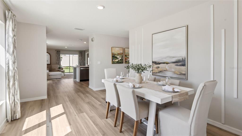 A dining room features a white table with six chairs, wall molding, and wood flooring — 24324 NW 10TH ROAD, NEWBERRY, FL