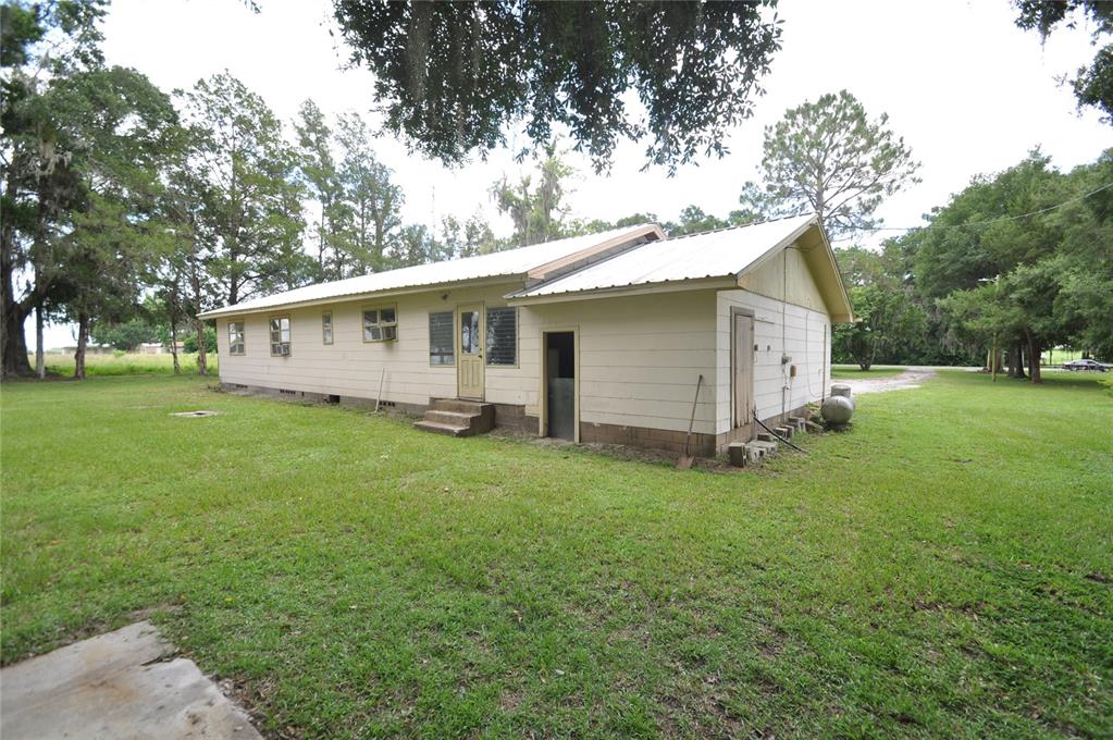A single-story house with light-colored siding and a metal roof sits on a grassy lot — 18491 NE STATE ROAD 121, WILLISTON, FL
