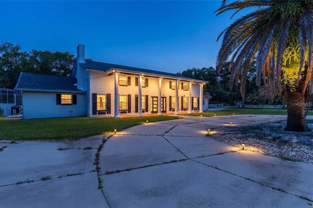 A white brick house with a large driveway, a basketball hoop, and a prominent oak tree — 2015 HALIFAX DRIVE, PORT ORANGE, FL