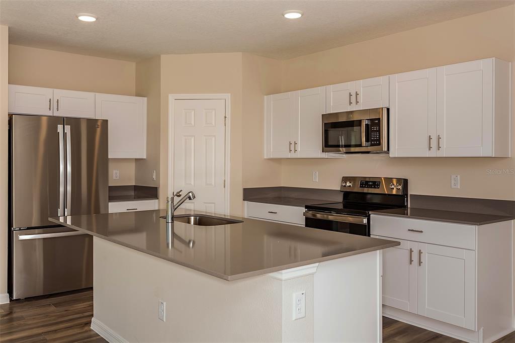 A kitchen features white cabinets, stainless steel appliances, a center island, and gray countertops — 5449 SAN PIETRO DRIVE, WINTER HAVEN, FL