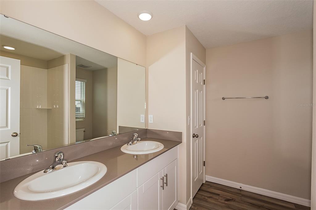 A bathroom features a double vanity with a brown countertop and white cabinets — 5449 SAN PIETRO DRIVE, WINTER HAVEN, FL