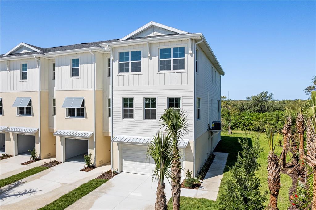 A three-story townhouse with white siding, a garage, and palm trees in the front yard — 7398 MARATHON DRIVE, SEMINOLE, FL