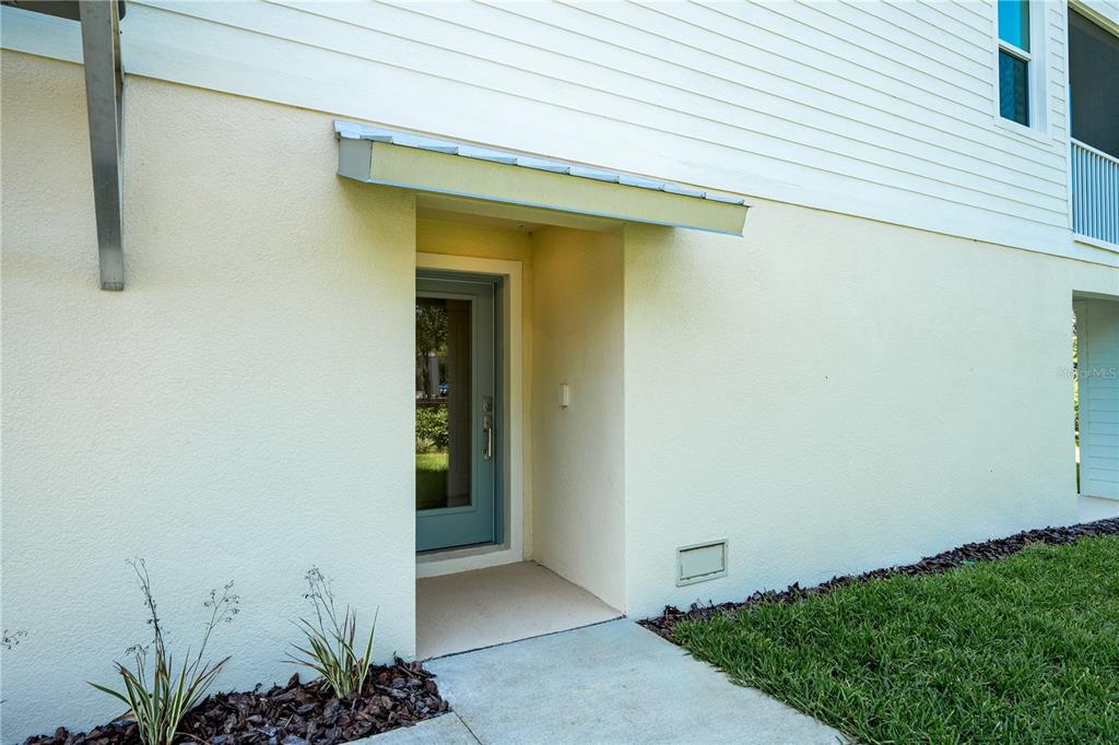 A light-colored exterior wall features a recessed entryway with a glass-paneled door and metal awning — 7398 MARATHON DRIVE, SEMINOLE, FL