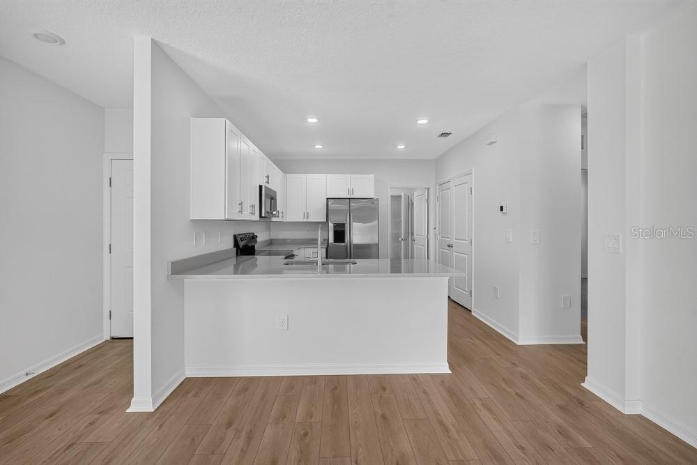 A kitchen features light gray cabinets, stainless steel appliances, and white countertops — 12219 TEMPEST LANE, HUDSON, FL