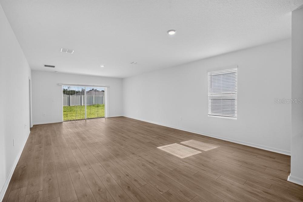 A modern kitchen with gray cabinets, stainless steel appliances, and an open-concept living area — 12219 TEMPEST LANE, HUDSON, FL
