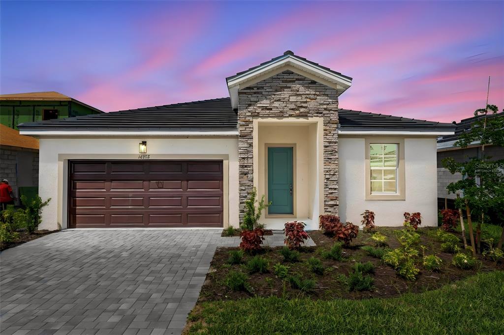 A single-story house with a stone-accented entryway, teal front door, and a paved driveway — 16938 SQUIRREL BRANCH LANE, ALVA, FL