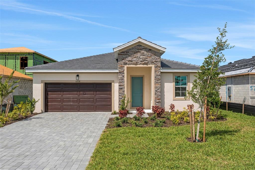 A single-story house with a stone facade, a brown garage door, and a teal front door — 16938 SQUIRREL BRANCH LANE, ALVA, FL