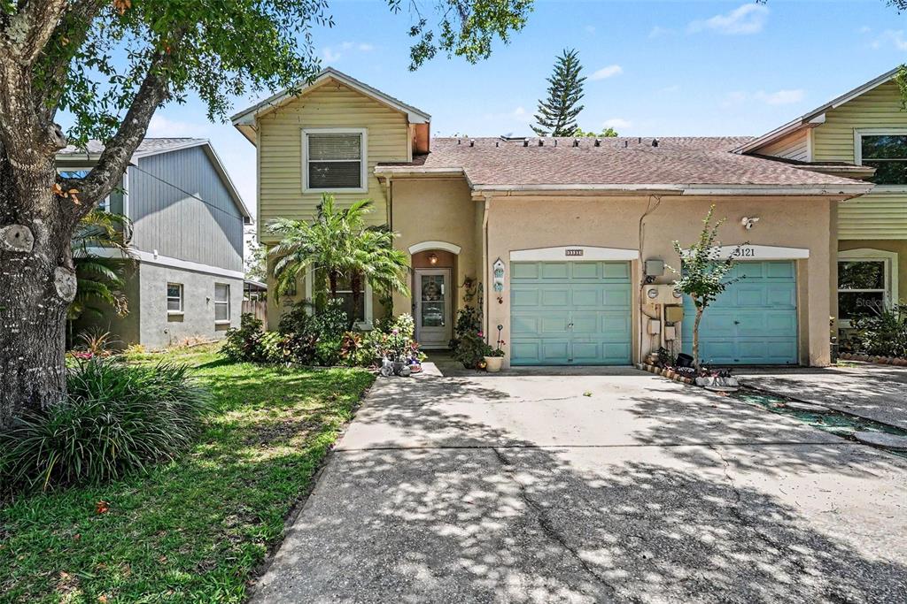 A two-story townhouse with a concrete driveway, two garage doors, and a small front garden — 5123 CORVETTE DRIVE, TAMPA, FL