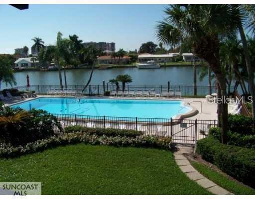 A view through sliding glass doors reveals a tiled patio with arched architectural columns — 507 PLAZA SEVILLE COURT UNIT 15, ST PETERSBURG, FL