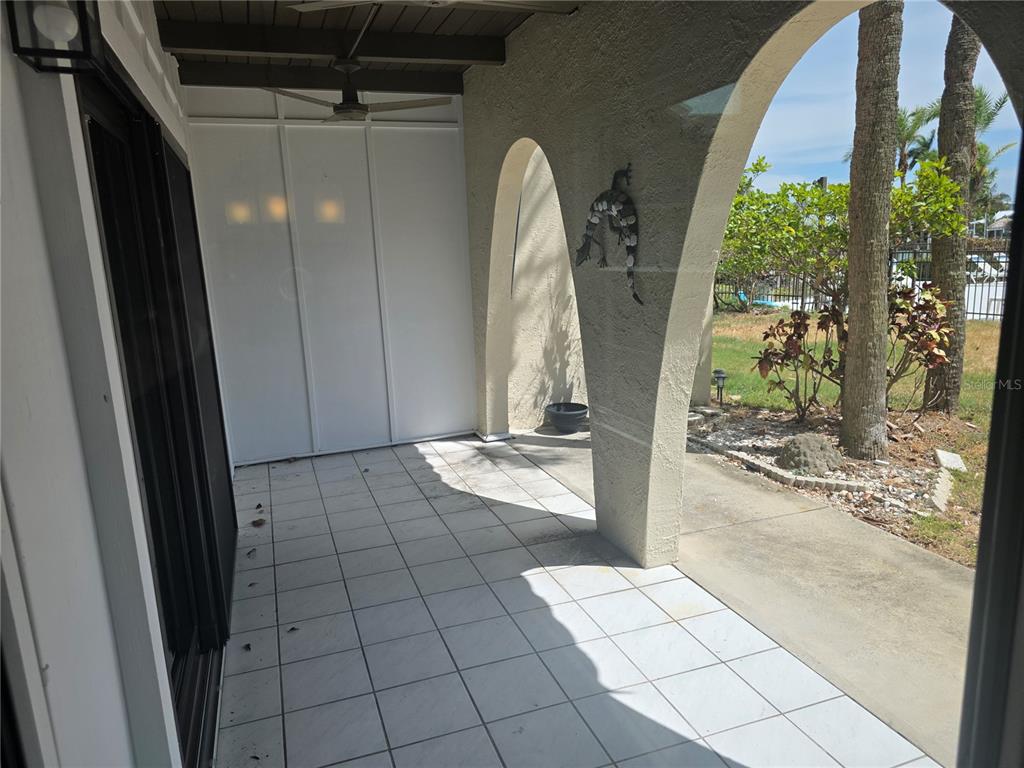 A covered patio features white tiled flooring, arched openings, and a decorative wall lizard — 507 PLAZA SEVILLE COURT UNIT 15, ST PETERSBURG, FL