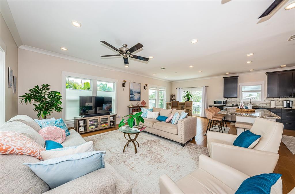 An open-concept living room features a beige sofa, two armchairs, and an adjacent kitchen area — 16109 3RD STREET E, REDINGTON BEACH, FL