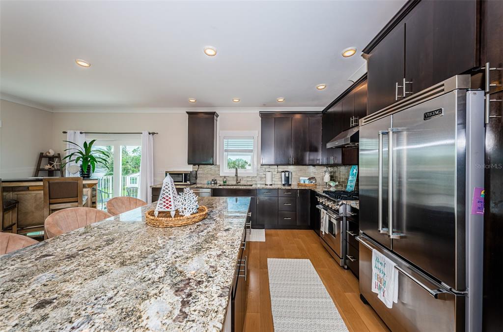 A kitchen features dark wood cabinets, granite countertops, stainless steel appliances, and a large island — 16109 3RD STREET E, REDINGTON BEACH, FL