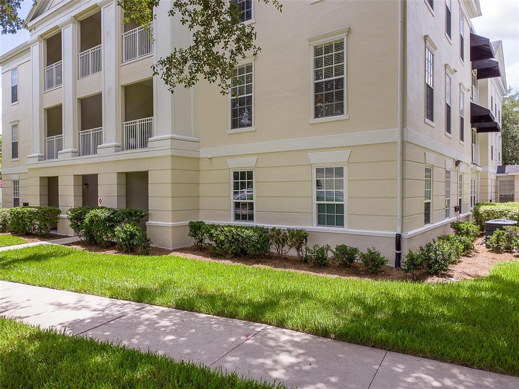 A multi-story apartment building exterior with beige stucco walls, white trim, and a sidewalk — 193 LONGVIEW AVENUE UNIT 103, CELEBRATION, FL
