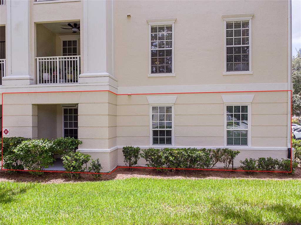 The exterior of a multi-story beige building features a ground-floor patio and two windows — 193 LONGVIEW AVENUE UNIT 103, CELEBRATION, FL