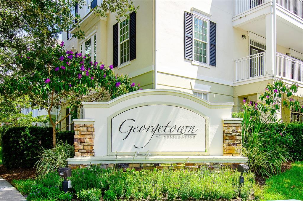 A stone and stucco sign for Georgetown at Celebration stands before a multi-story apartment building — 193 LONGVIEW AVENUE UNIT 103, CELEBRATION, FL