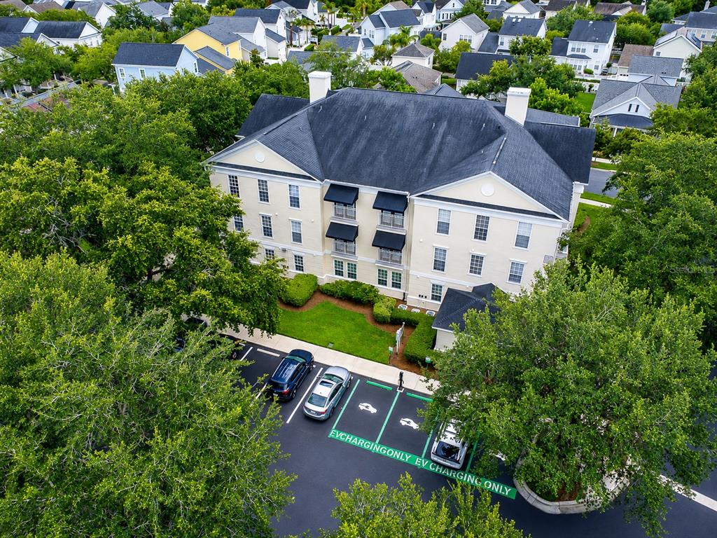 An aerial view shows a multi-story apartment building with dedicated electric vehicle charging parking spaces — 193 LONGVIEW AVENUE UNIT 103, CELEBRATION, FL