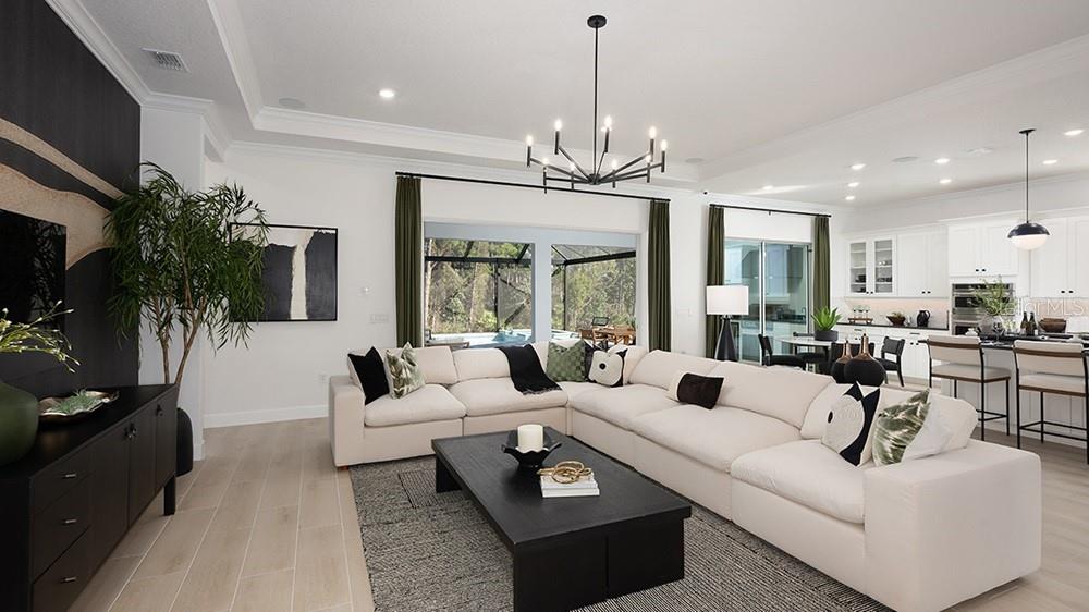 A modern kitchen features white cabinetry, a marble-topped island with bar stools, and stainless appliances — 997 TASSLEFLOWER TRAIL, ST CLOUD, FL