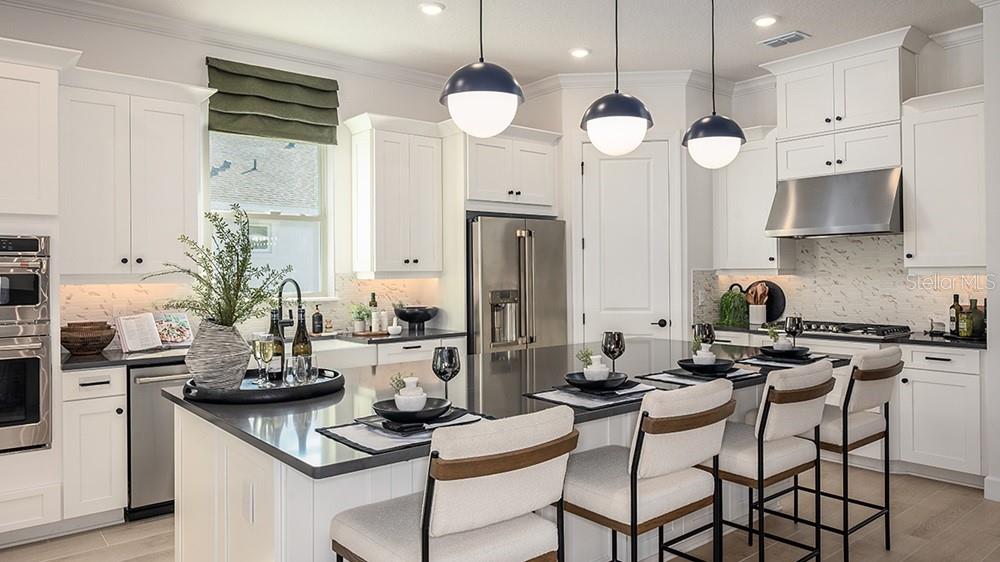 A modern white kitchen features a large island, stainless steel appliances, and three pendant lights — 997 TASSLEFLOWER TRAIL, ST CLOUD, FL